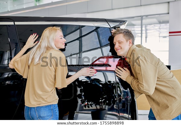 dreams come true,\
beautiful caucasian married couple buy new car in dealership, they\
hug big black auto