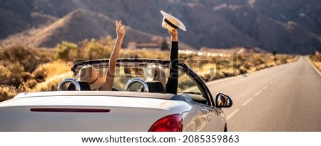Dreams come true! Two happy young girls driving cabrio car during vacation road trip in mountains, making memories and having fun together. Back view.Freedom concept. Happiness. Tourist. 
