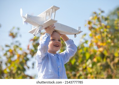 Dreams Of Flight. Child Playing With Toy Plane Against The Sky. Dreams Of Travels. Little Dreaming Child With A Toy Airplane Plays Outdoors. Blonde Kid, Smiling Emotion Face.