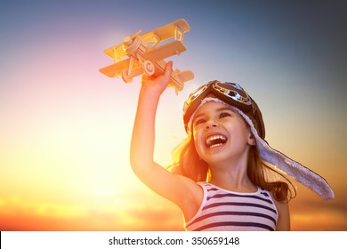 Dreams Of Flight! Child Playing With Toy Airplane Against The Sky At Sunset