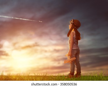 Dreams Of Flight! Child Playing With Toy Airplane Against The Sky At Sunset