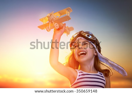 dreams of flight! child playing with toy airplane against the sky at sunset