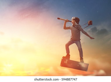 Dreams of travel! Child flying on a suitcase against the backdrop of sunset. - Shutterstock ID 594887747