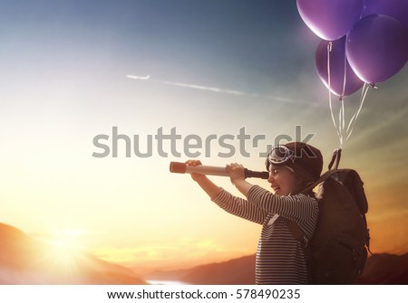Dreams of travel! Child flying on balloons against the backdrop of a sunset.