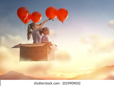 Dreams of travel! Two children are flying in cardboard box with air balloons.