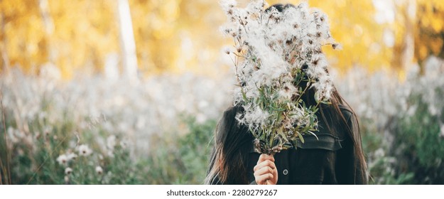 Dreamy beautiful girl on bokeh background of yellow leaves. Inspired girl with white thistle flowers bouquet in autumn forest. Girl hiding her face behind thistle flowers bouquet among autumn foliage. - Shutterstock ID 2280279267