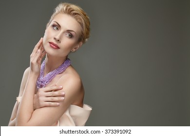 Dreamy beauty. Portrait of a beautiful mature female embracing herself looking away posing against grey background copyspace on the side