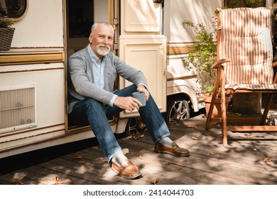 Dreamy brave old senior explorer traveler adventurer relaxing on the porch of trailer motor home camper van. Traveling alone, solo trip going away from everything