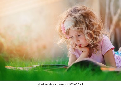 Dreamy Child Girl Learning On Summer Vacation And Reading Book In The Garden