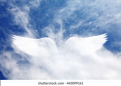 A dreamy cloudy blue sky with a surreal angel wings shape cloud apparition.
