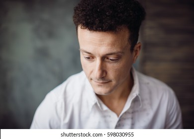Dreamy curly man looks down