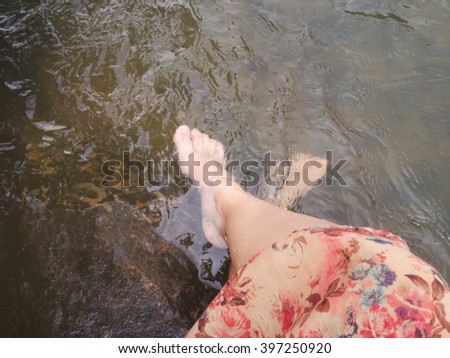 Dreamy fantasy colour lifestyle, Women in flowers dress sit and dip feet in crystalline stream, summer relaxing feeling