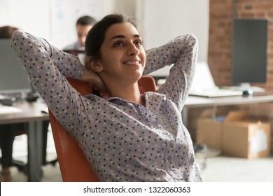 Dreamy happy indian businesswoman relaxing taking break at work, calm smiling hindu lady resting sitting in ergonomic chair dreaming hands behind head breathing fresh air feel no stress enjoy balance