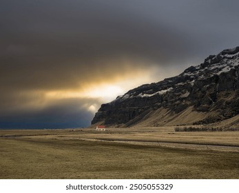 Dreamy Icelandic cottage nestled amidst rolling green hills, snow-capped mountains in the distance, in stormy weather. - Powered by Shutterstock