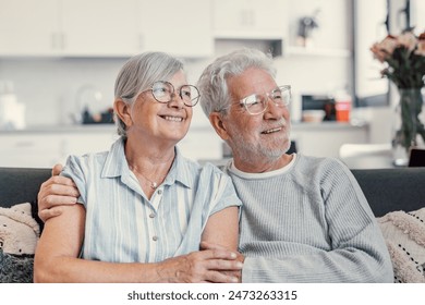 Dreamy middle aged senior loving retired family couple looking in distance, planning common future or recollecting memories, enjoying peaceful moment relaxing together on cozy sofa in living room - Powered by Shutterstock