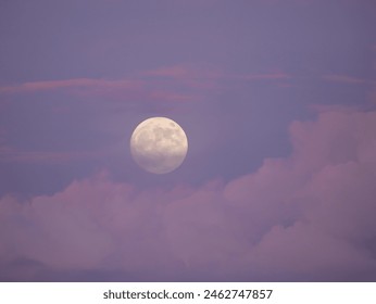 Dreamy moment of a big rising full moon above pink colored cloud in a blue sky. Amazing colors of blue hour after summer sunset. Magnificent view of mystic moonrise among colorful stormy clouds. - Powered by Shutterstock