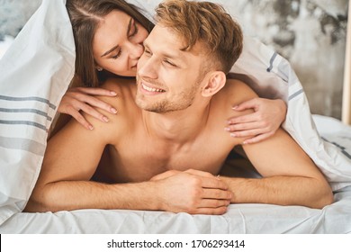 Dreamy Mood. Tender Young Woman Lying On Her Man And Kissing His Cheek With Pleasure