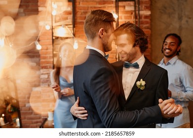 Dreamy portrait of young gay couple dancing together during wedding reception with lens flare - Powered by Shutterstock