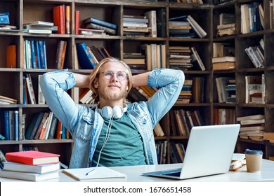 Dreamy relaxed young millennial man student hold hands behind head looking away dreaming sit at library desk thinking of new ideas inspiration opportunities meditating feel peace of mind concept.