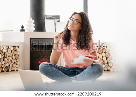 Dreamy thoughtful pensive young woman author student doing paperwork, writing poetry novels at home using laptop, preparing for test exam