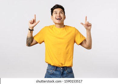 Dreamy Very Happy Handsome Young Asian Man In Yellow T-shirt, Pointing Looking Up Amused With Enthusiastic, Excited Expression, Found Exactly What Need, See Beautiful Thing, White Background