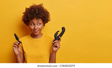 Dreamy woman enjoys sexual life poses with butt plug and rabbit shaped vibrator to satisfy all types of preferences address all important areas of body, advertises sex toys for adults empy place aside