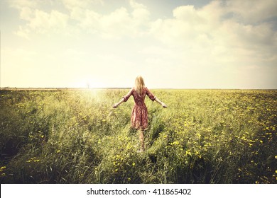 dreamy woman walking in nature towards the sun