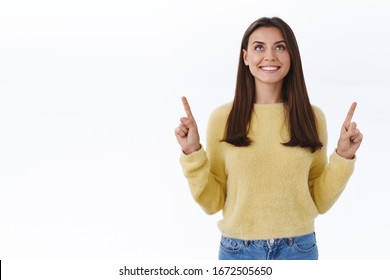 Dreamy young woman gratuate university searching her path in life, apply job found exactly what she needed, look and pointing fingers up with satisfied happy smile, stand white background