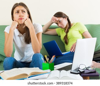 Dreary teenage student girls study at home with the books and computers 