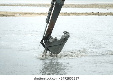 A dredge backhoe is perform dredging into the coastline floor. Industrial working scene, close-up. 