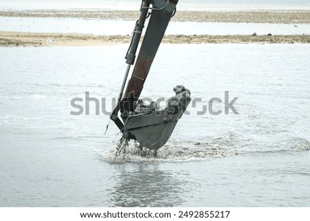 A dredge backhoe is perform dredging into the coastline floor. Industrial working scene, close-up. 