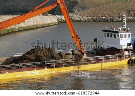 Dredging ship scooping soil from River Esk in Whitby