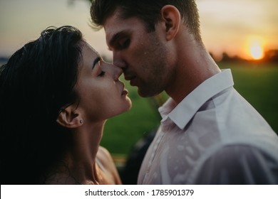 Drenched Couple In Love Kisses And Embraces Under Drops Of Rain At Sunset. Portrait.