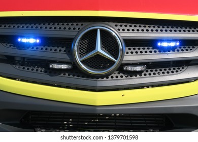 Dresden, Germany, 04-18-2019, a part of the front of a Mercedes ambulance with the blue lights or strobe lights, the logo of the Mercedes company is in the center of the front part