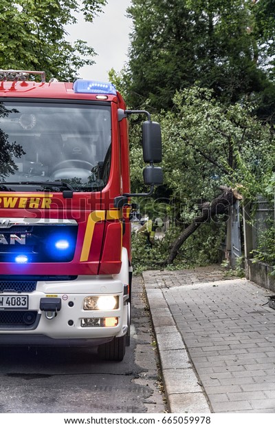 Dresden, Saxony,\
Germany - 22 June 2017: German emergency fire truck (Feuerwehr\
Dresden) on the road. Fire service after a storm with uprooted\
trees in Dresden\
Striesen.