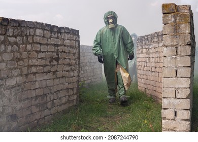 Dressed in a Soviet chemical protection suit and a gas mask, a man walks along the ruins through thick smoke. Radiation hazard and consequences of pollution of the environment concept. Selective focus