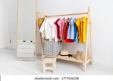 Dressing Closet With Clothes Arranged On Hangers. Colorful Wardrobe Of Newborn, Kids, Toddlers, Babies Full Of All Clothes. Montessori Wardrobe.