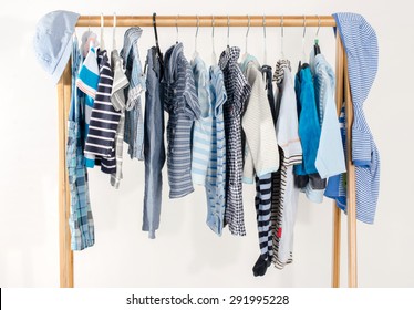 Dressing Closet With Clothes Arranged On Hangers.Blue And White Wardrobe Of Newborn,kids, Toddlers, Babies Full Of All Clothes.Many T-shirts,pants, Shirts,blouses,blue Hat, Onesie Hanging