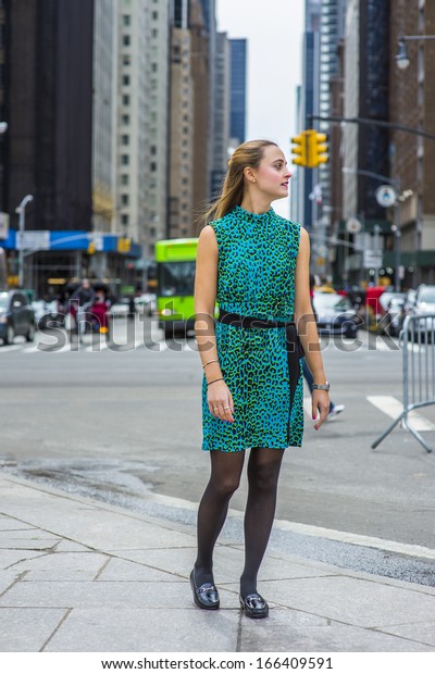 Dressing\
in green and black patterned sleeveless dress, black leggings,\
leather shoes and a black waist strap, a happy girl is standing on\
a busy street of a big city. / Looking for You.\
