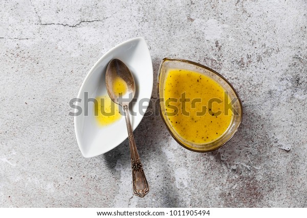 dressing for salad from olive oil\
and lemon in a serving dish and a silver spoon on a stone\
table