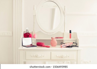 Dressing table with different makeup products and accessories in room interior

