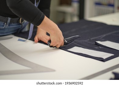 Dressmaker cutting dress fabric on sketch line. Fashion designer tailor or sewer in workshop studio designing new collection clothes. Business owner shop and entrepreneur concept