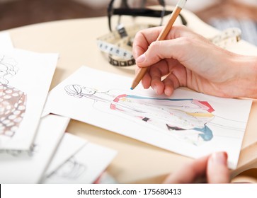 Dressmaker is drawing a fashion sketch. Close up of the hands - Powered by Shutterstock