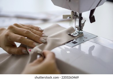 The dressmaker elaborately made a  thread pattern on a fine beige fabric. Close up