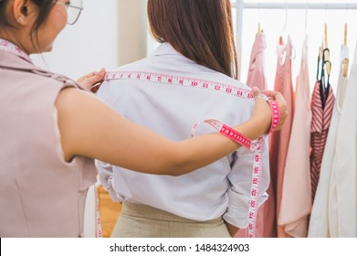 Dressmaker measuring female customer shoulder in sewing atelier workshop office. Tailor and fashion designer concept. Job and freelance occupation. Business people in clothing shop