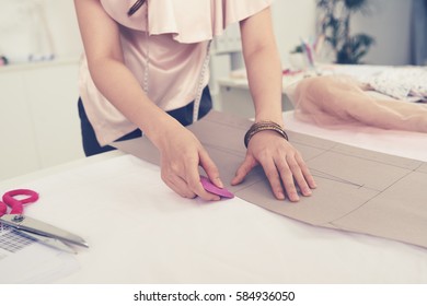 Dressmaker outlining pattern of jacket on cloth
