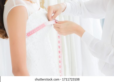 The Dressmaker Is Using A Tape Measure To Measure The Bust Size Of A Female Customer Who Ordered A Wedding Dress At A Tailor Shop.