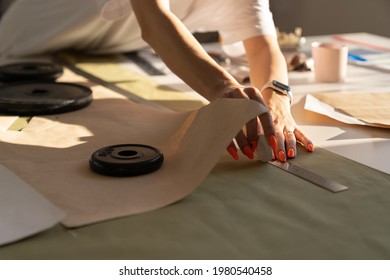 Dressmaking process in atelier: female tailor drafting clothes model on fabric for cutting patterns of cloth. Closeup shot of woman sewer hold chalk while working on designer workshop. Sewing business - Shutterstock ID 1980540458