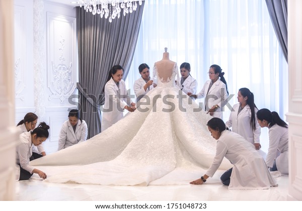 Dressmaking. Team of female workers\
making a big beautiful haute couture bridal wedding dress.\

