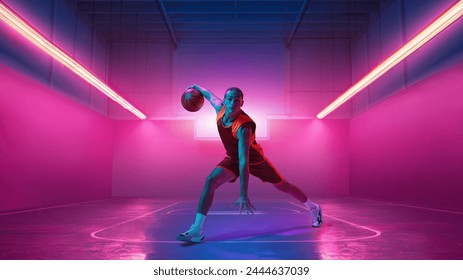 Dribbling ball. Young man in uniform basketball player in motion against gradient indoor stadium background in neon light. Concept of sport, action, game, competition, tournament, energy. Poster, ad - Powered by Shutterstock